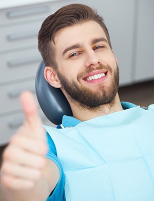 Smiling man in dental chair giving thumbs up